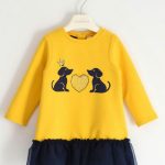 Abito bimba balza tulle Abito per bambina a manica lunga realizzato in felpa stretch garzata internamente con stampa cagnolini illuminati da cuore di strass. Il modello ha la balza sul fondo in tulle, foderata in jersey di cotone. Apertura dietro con bottoni. Lunghezza mini.