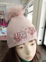 Cappello bimba Bettina Cappello in maglia rasata con dettagli lurex, foderato in pile - 100% cotone, pompon in ecopelliccia e decoro fiori.