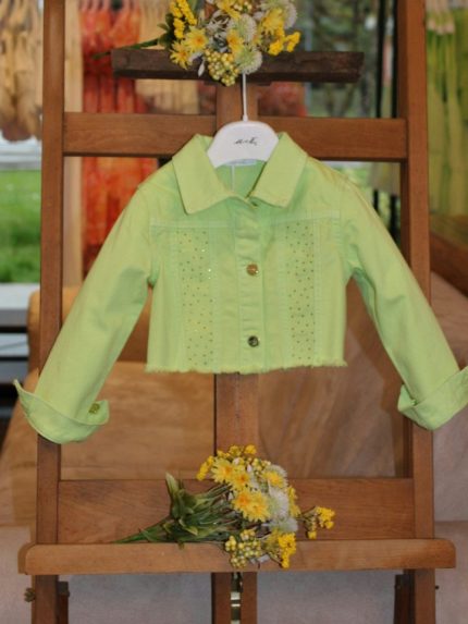 Giubbotto jeans bimba Giubbotto jeans bimba con colletto camicia, allacciatura a bottoni, fondo sfrangiato, motivo strass applicati sul davanti.