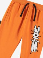 Pantaloni felpa Joggers in felpina elasticizzata tinta unita arancione con tasche laterali e polsini al fondo, cintura elastica con coulisse, stampa "doodle shoe" bianca posizionata in verticale sulla gamba sinistra. Vestibilità regolare.