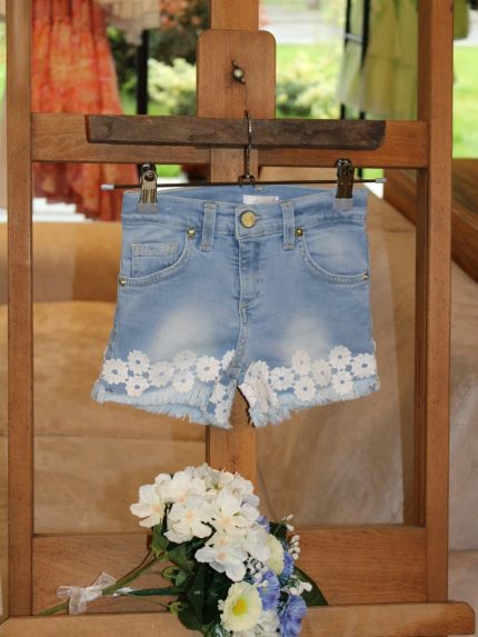 Shorts bimba Shorts in denim modello cinque tasche, vita regolabile con elastico interno, allacciatura a bottone, decoro macramè applicato e fondo sfrangiato.